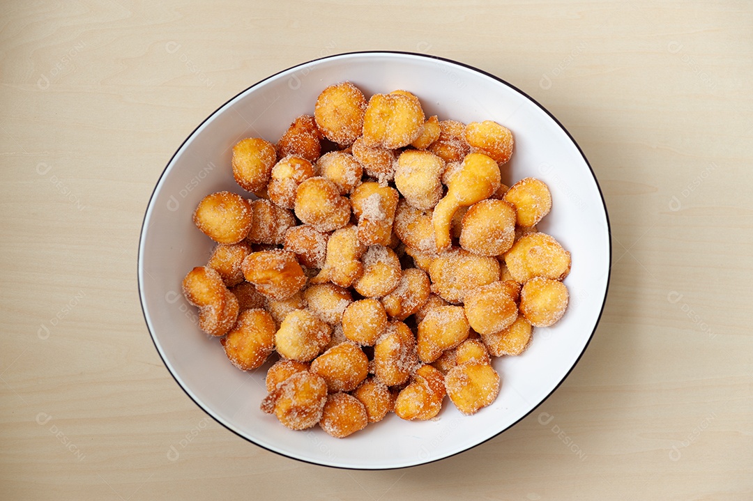 Delicioso e tradicional doce brasileiro caseiro chamado Bolinho de Chuva em um prato. Isolado em fundo de madeira. Vista do topo. Copiar espaço