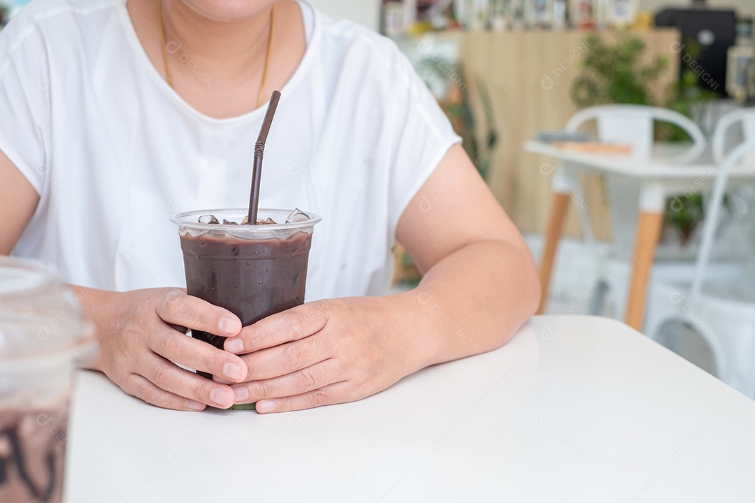 Mulher asiática de camisa branca sentada à mesa de madeira branca, segurando a xícara de café na cafeteria. copie o espaço, relaxe o conceito de tempo