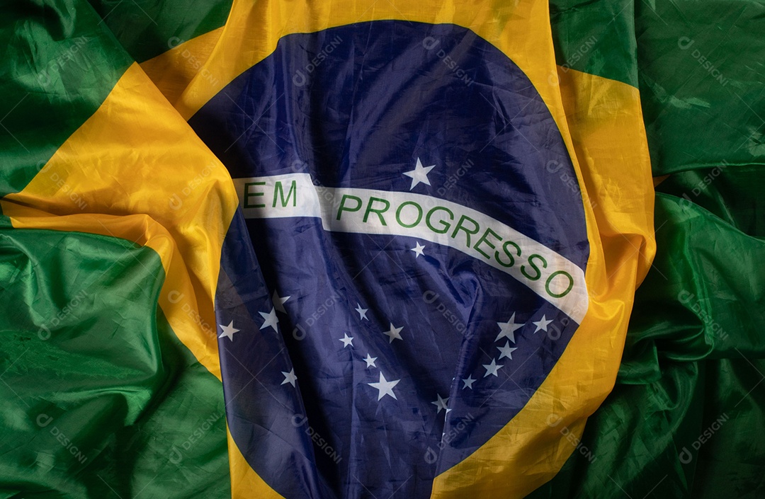 Feche acenando a bandeira do brasil ao vento. Tecido amassado da bandeira brasileira com a frase ordem e progresso.