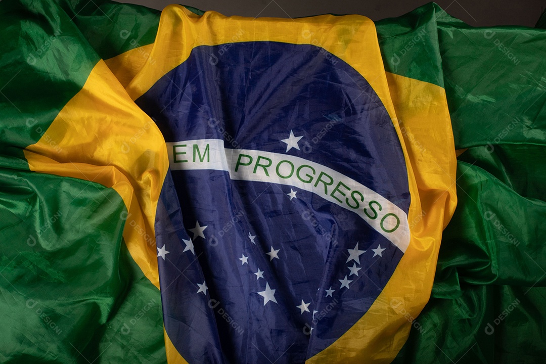 Feche acenando a bandeira do brasil ao vento. Tecido amassado da bandeira brasileira com a frase ordem e progresso.