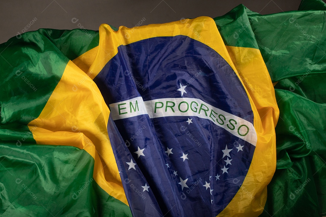 Feche acenando a bandeira do brasil ao vento. Tecido amassado da bandeira brasileira com a frase ordem e progresso.