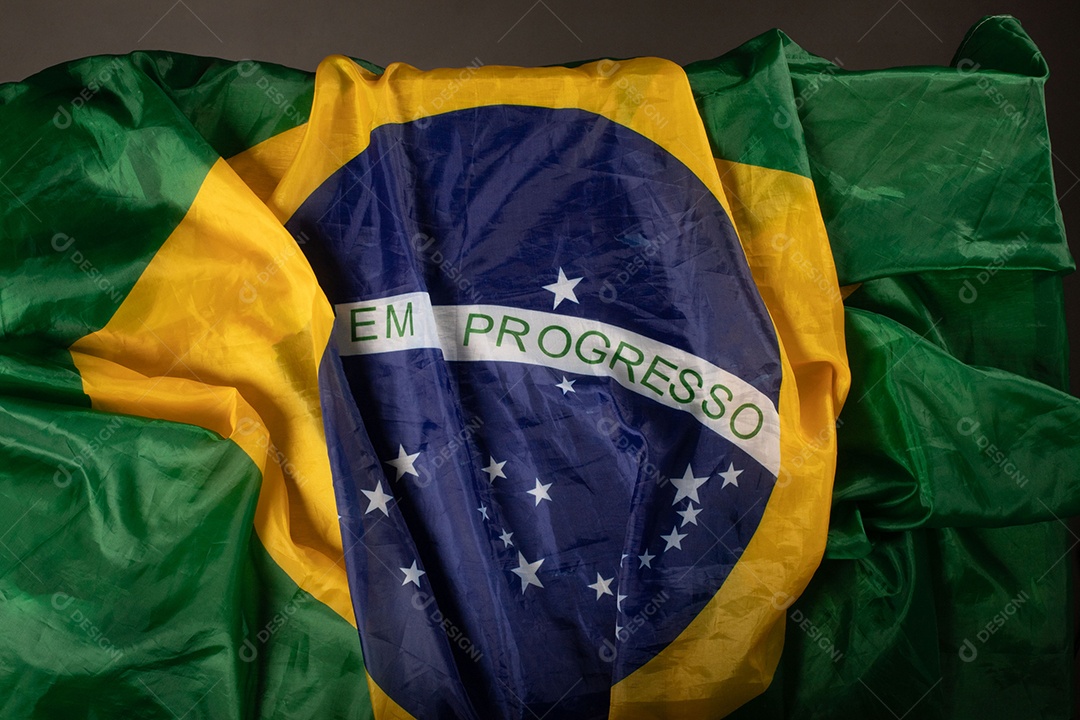 Feche acenando a bandeira do brasil ao vento. Tecido amassado da bandeira brasileira com a frase ordem e progresso.