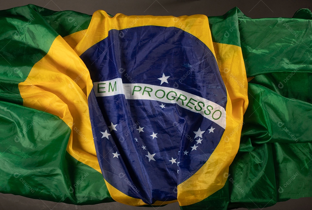 Feche acenando a bandeira do brasil ao vento. Tecido amassado da bandeira brasileira com a frase ordem e progresso.