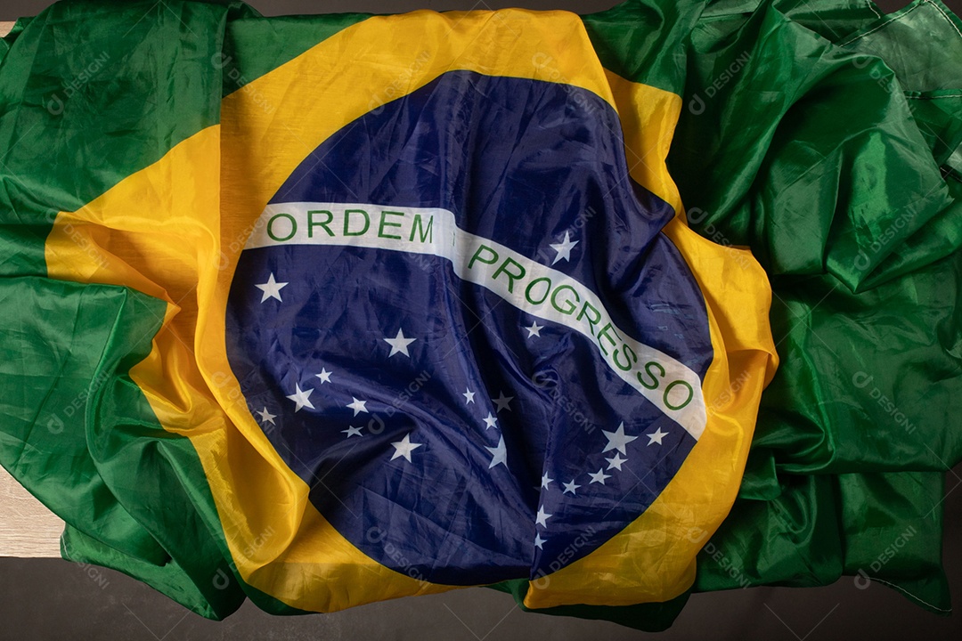 Feche acenando a bandeira do brasil ao vento. Tecido amassado da bandeira brasileira com a frase ordem e progresso.