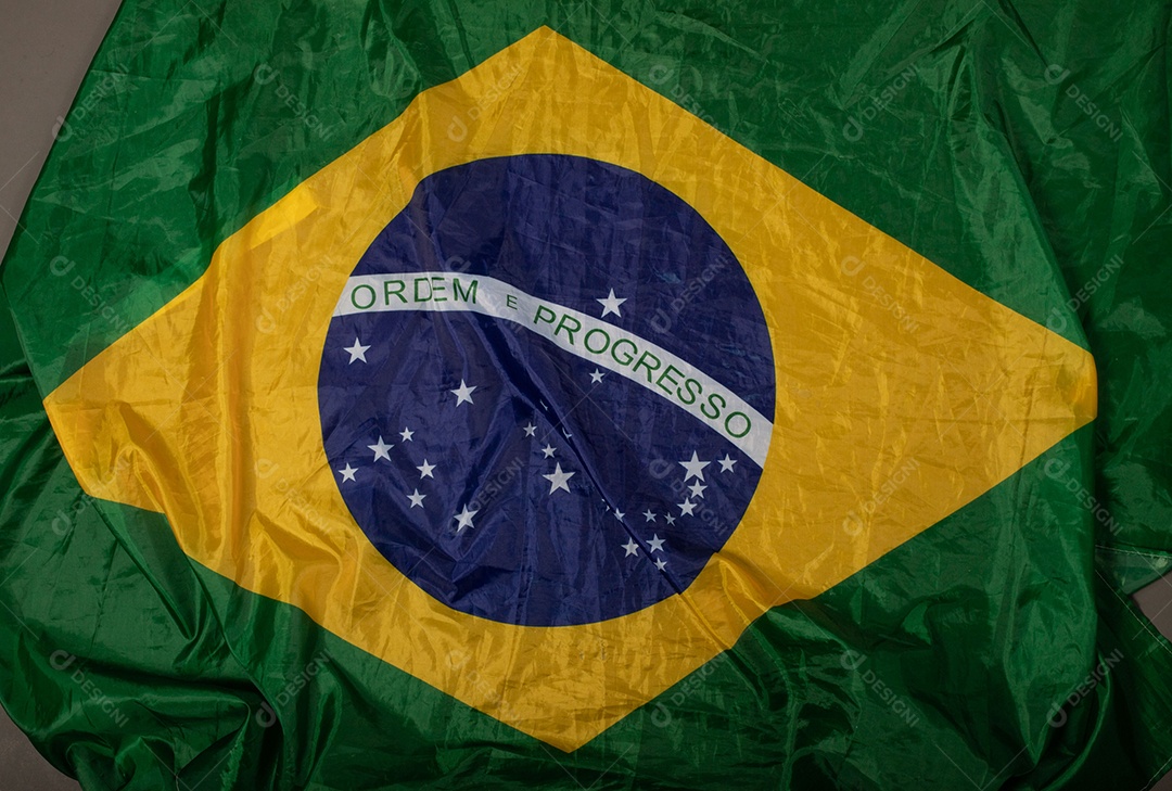 Feche acenando a bandeira do brasil ao vento. Tecido amassado da bandeira brasileira com a frase ordem e progresso.