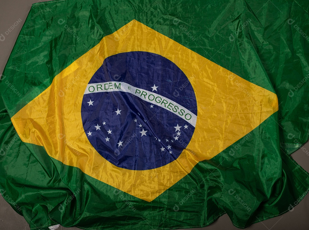 Feche acenando a bandeira do brasil ao vento. Tecido amassado da bandeira brasileira com a frase ordem e progresso.