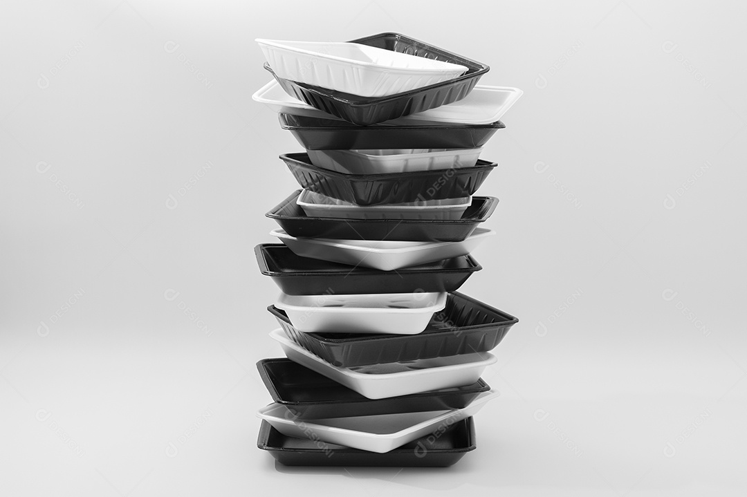 Bandejas de recipientes de alimentos de espuma branca e preta (bandejas de isopor) empilhadas. Isolado no fundo branco. Fechar-se. Copie o espaço. Tiro horizontal.