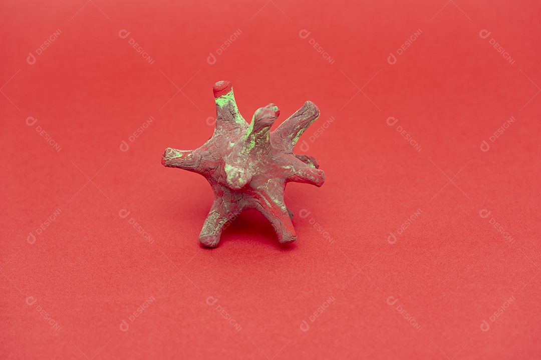 Modelo coronavírus feito com massa de modelar vermelha e verde (DIY). Isolado em fundo vermelho. Fechar-se. Tiro horizontal.