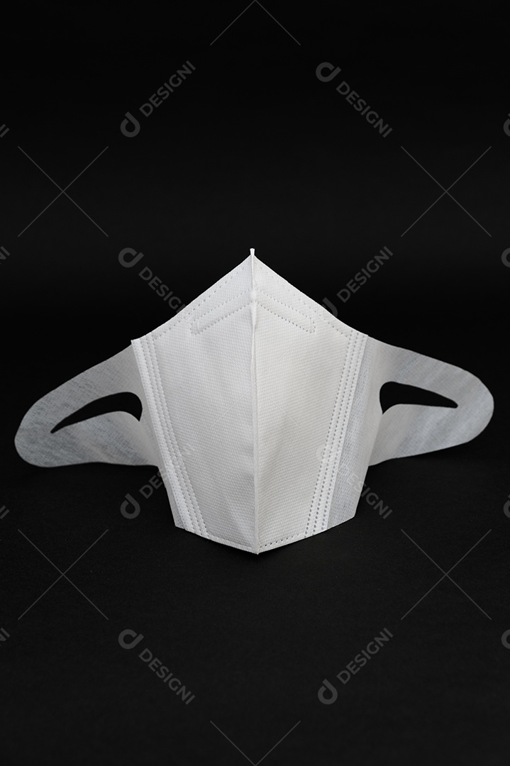 Máscara cirúrgica branca para proteção contra coronavírus (COVID-19) e outras doenças infecciosas. Isolado em fundo preto. Fechar-se. Copie o espaço. Tiro vertical.