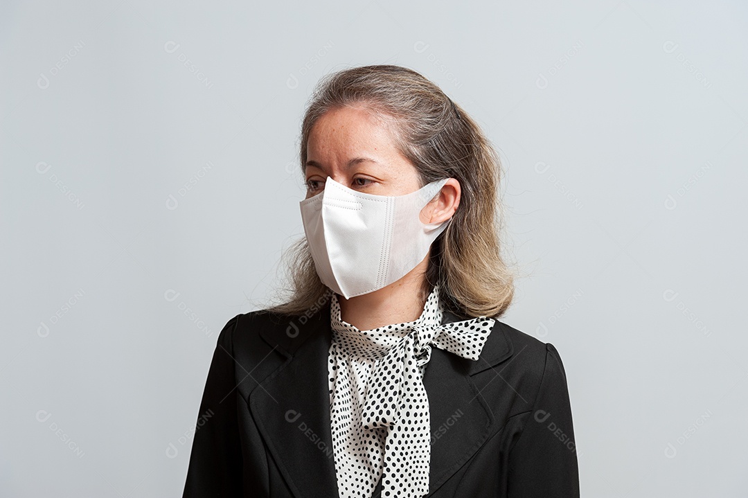 Vista lateral da mulher mestiça de meia idade com roupa formal usando máscara cirúrgica branca para proteção contra coronavírus (COVID-19). Isolado no fundo branco. Vista lateral.