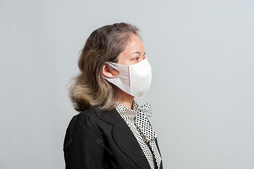 Vista lateral da mulher mestiça de meia idade com roupa formal usando máscara cirúrgica branca para proteção contra coronavírus (COVID-19). Isolado no fundo branco. Vista lateral.