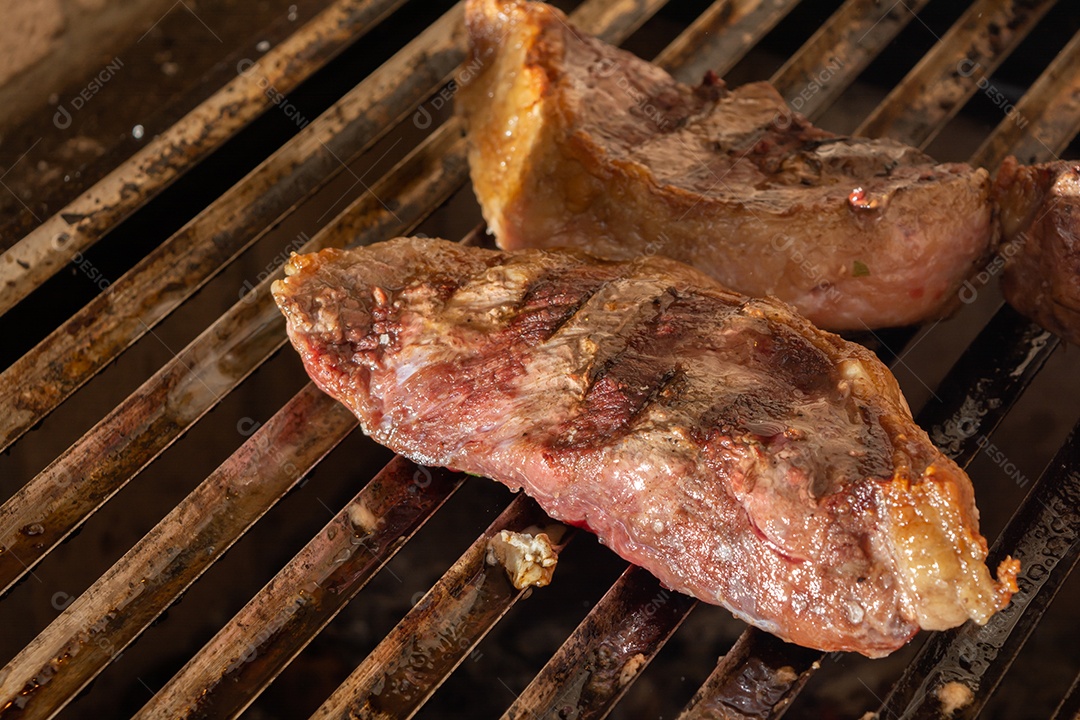 bifes de picanha e linguiça na grelha quente. maior ângulo