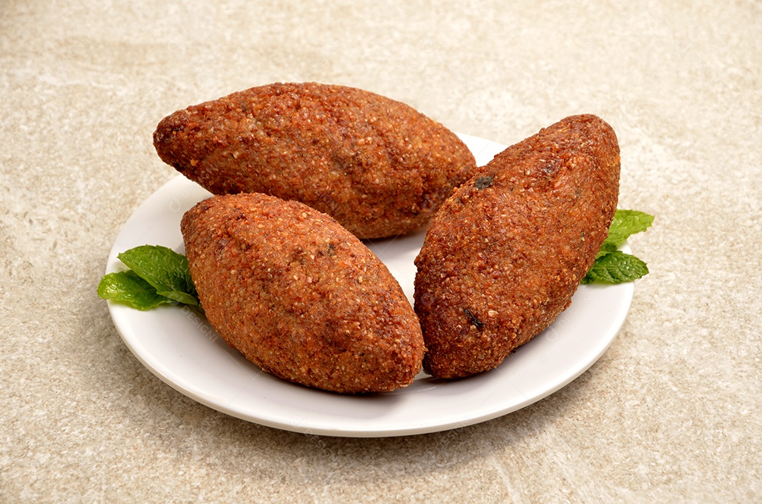 Quibes fritos sobre um prato branco mesa madeira