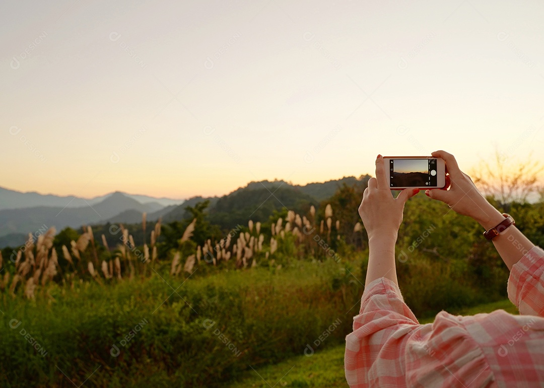 Jovem mulher asiática tirando uma foto com seu telefone em lindo pôr do sol