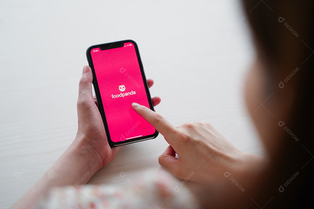 Mulher usando iPhone mostrando o aplicativo Foodpanda na tela