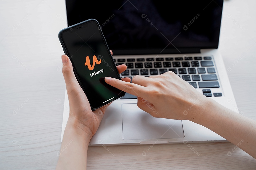IPhone mostrando o aplicativo Udemy e o laptop.