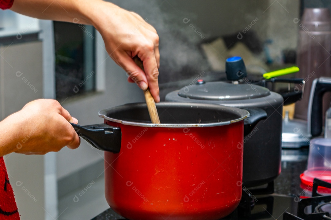 mulher mexendo panela com colher de pau, fumaça quente