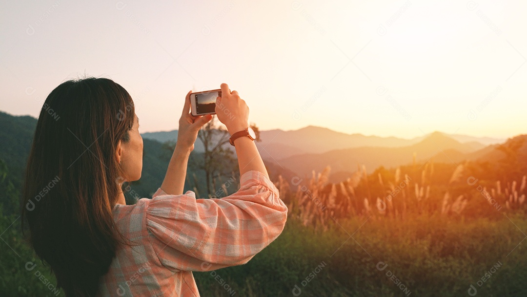 Jovem mulher asiática tirando uma foto com seu smartphone na bela