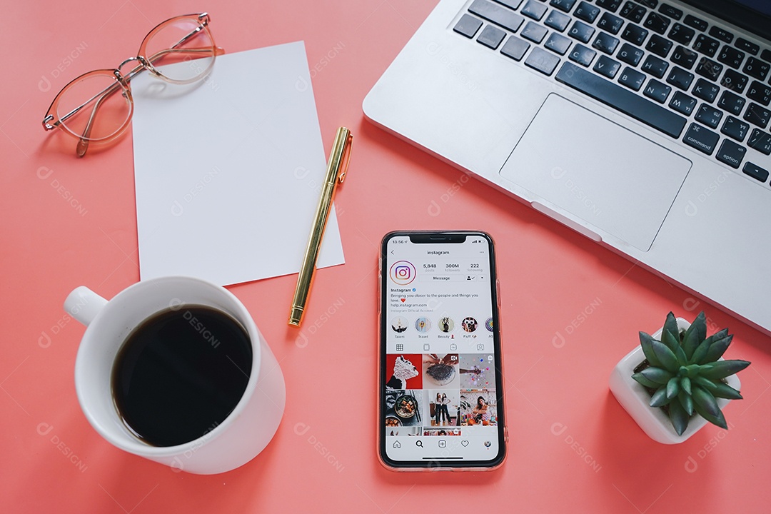 Mesa de trabalho plana e Apple iPhone XS com aplicativo Instagram na tela com laptop e fundo de café.