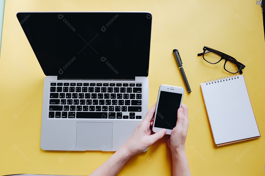 Postura plana da mesa do espaço de trabalho com mãos de mulher digitando no laptop com inteligência