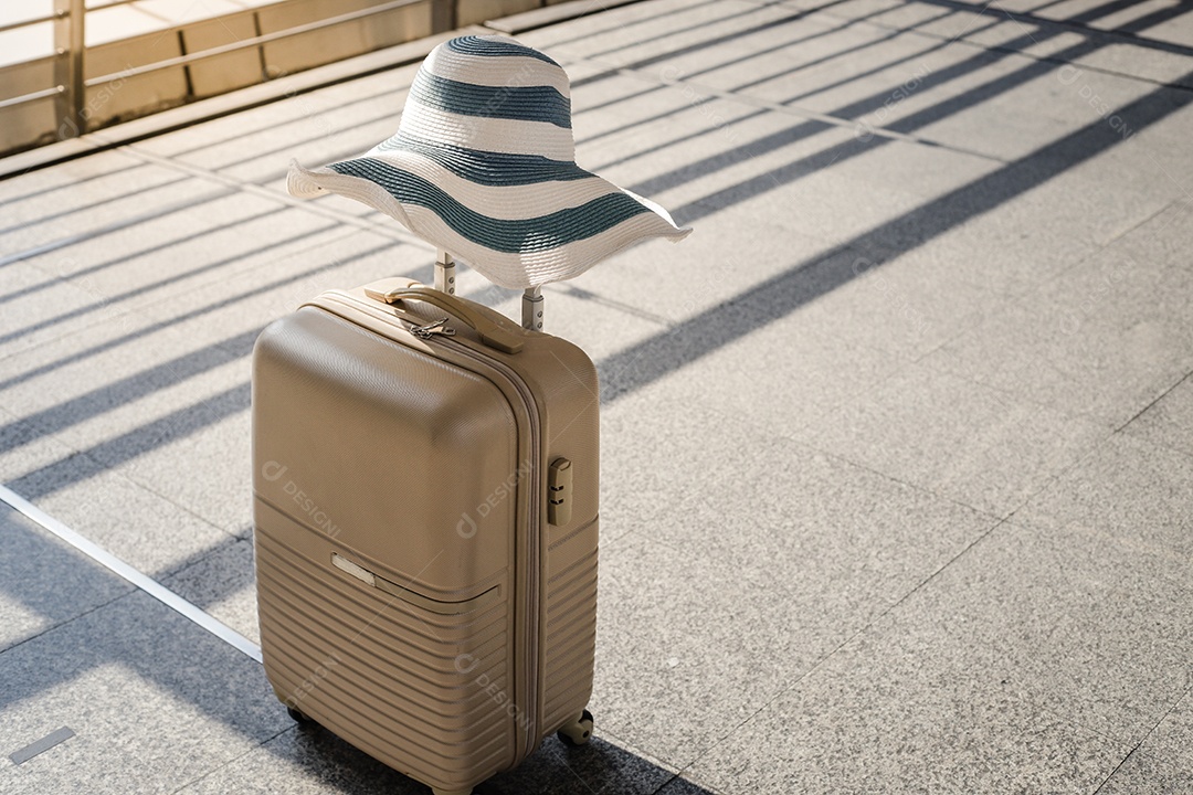 Uma mala com chapéu de verão na sala de embarque do aeroporto