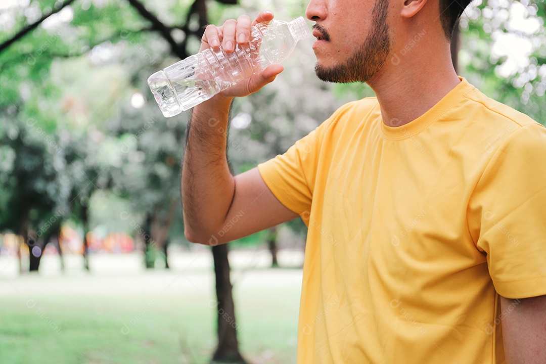 Jovem asiático corredor bebendo água da garrafa após exercício duro no jardim