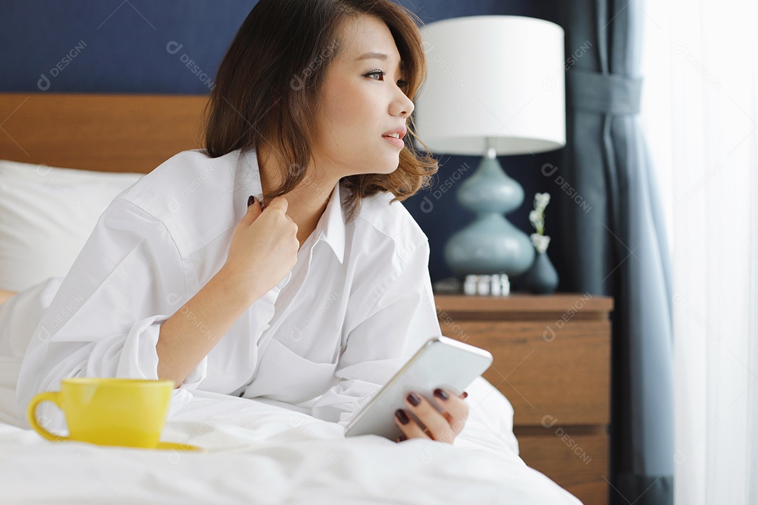 Jovem mulher atraente asiática usando smartphone e bebendo café