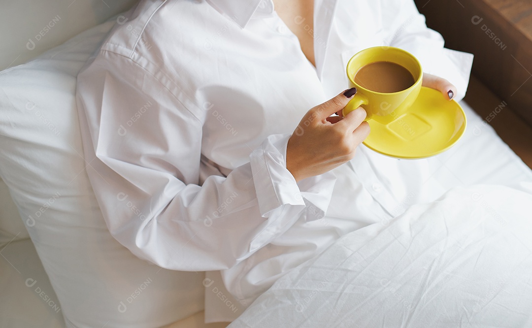 Café da manhã na cama, jovem mulher asiática segurando xícara de café quente