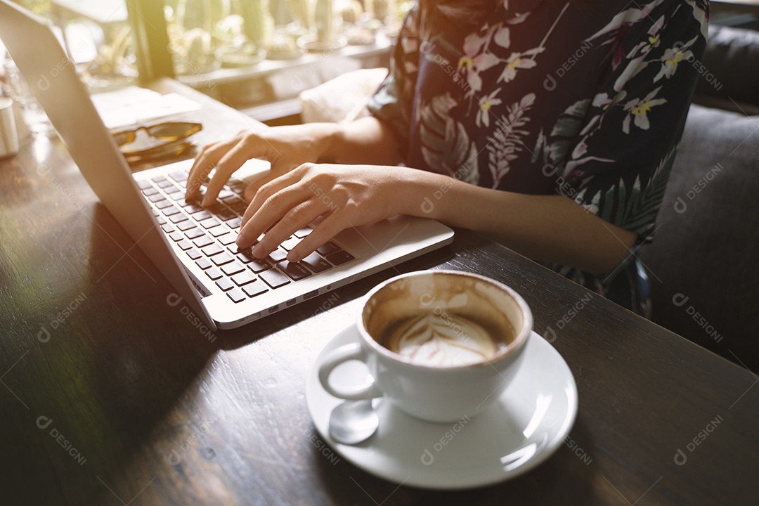Mulher asiática hipster usando laptop no café com luz solar