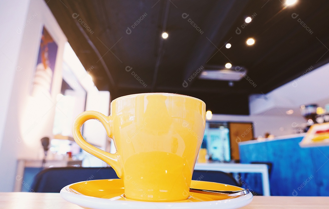 Xícara amarela em mesa de cafeteria