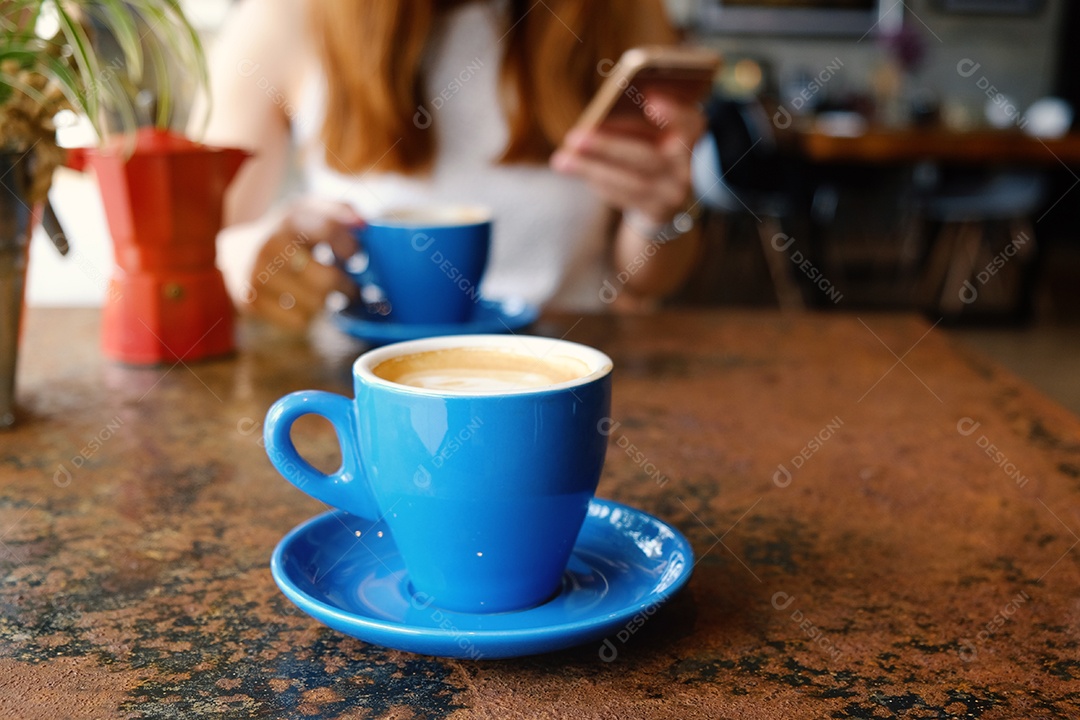 Xícara azul com bebida quente sobre mesa na cafeteria