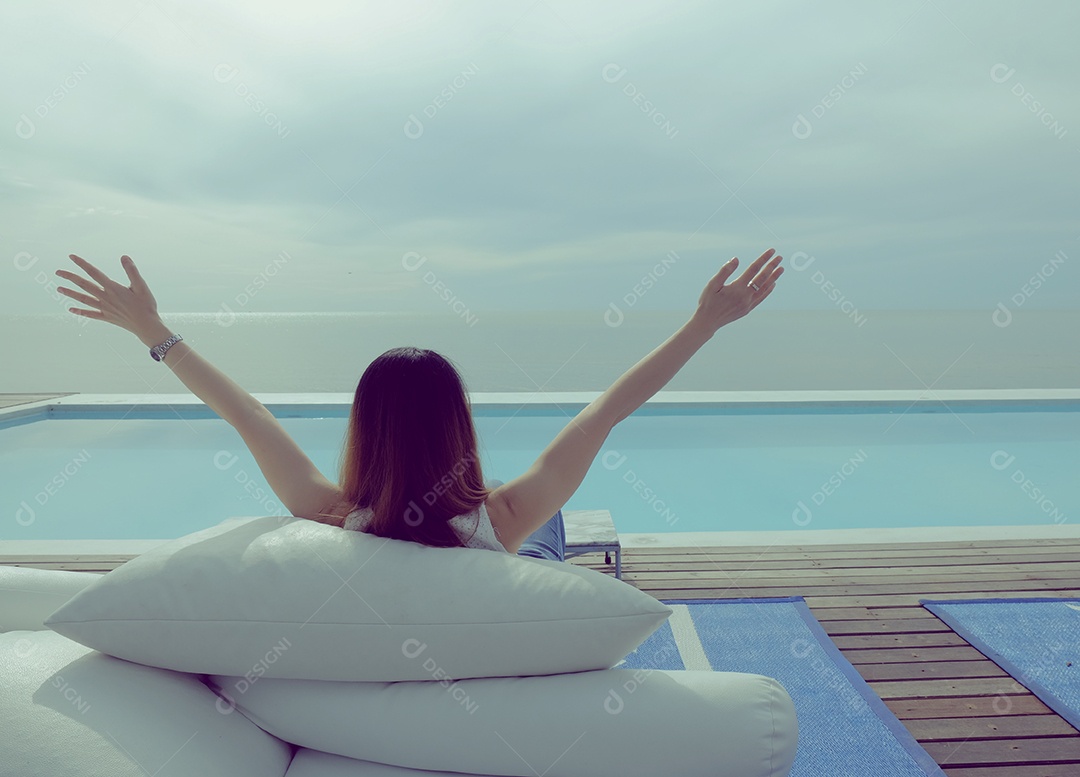 Mulher deitada em almofadas na beira da piscina relaxando