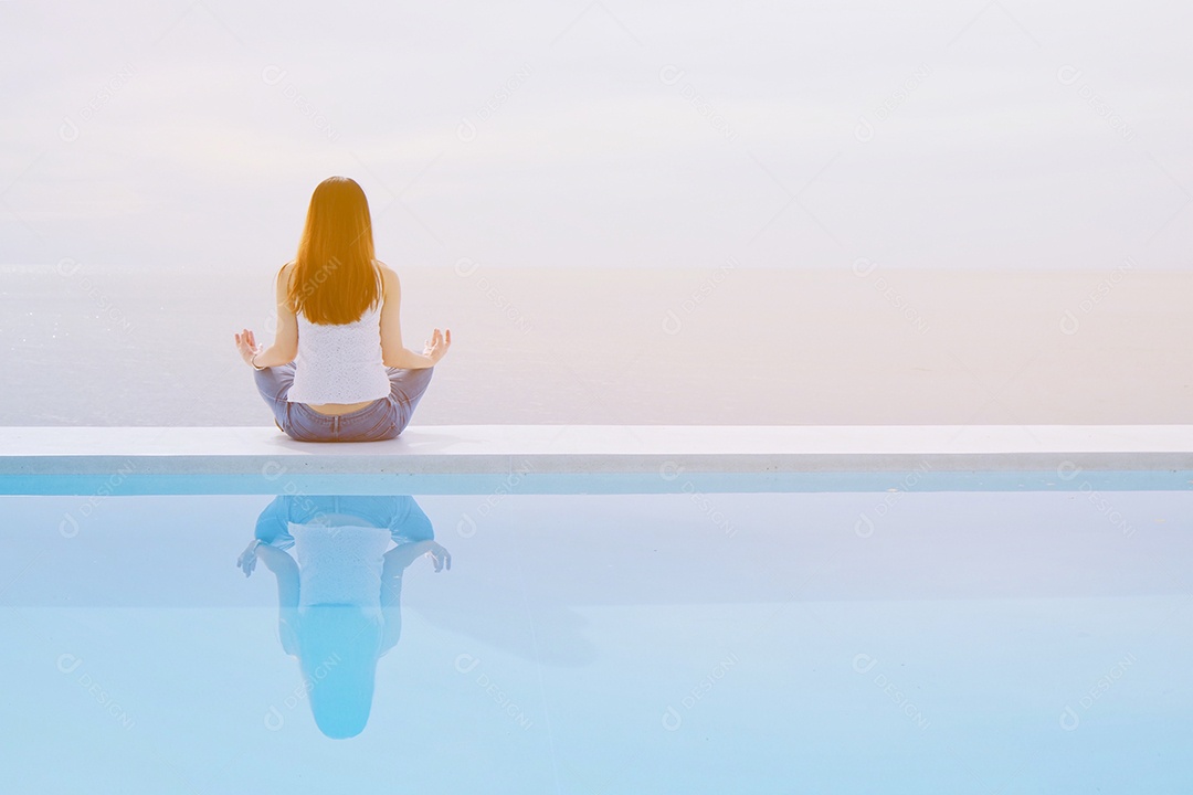 Mulher sentada na beira da piscina meditando