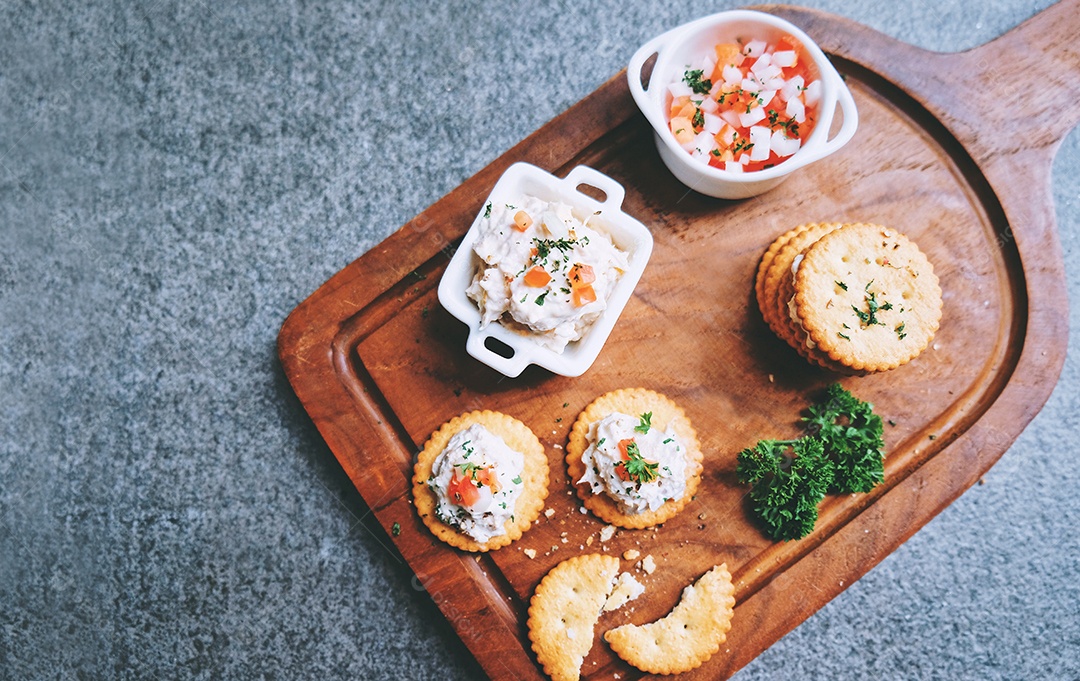 Vista superior do saboroso atum espalhado com bolachas na bandeja de madeira
