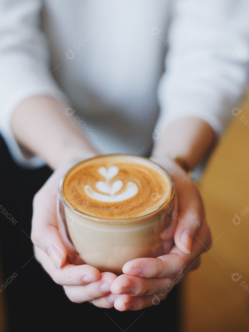 Feche as mãos da mulher barista segurando uma xícara de café cappuccino quente no café