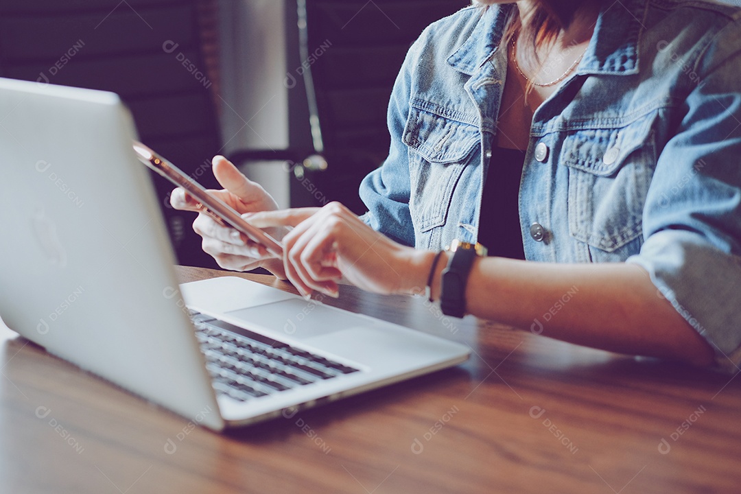 Mulher jovem hipster usando smartphone e laptop no escritório