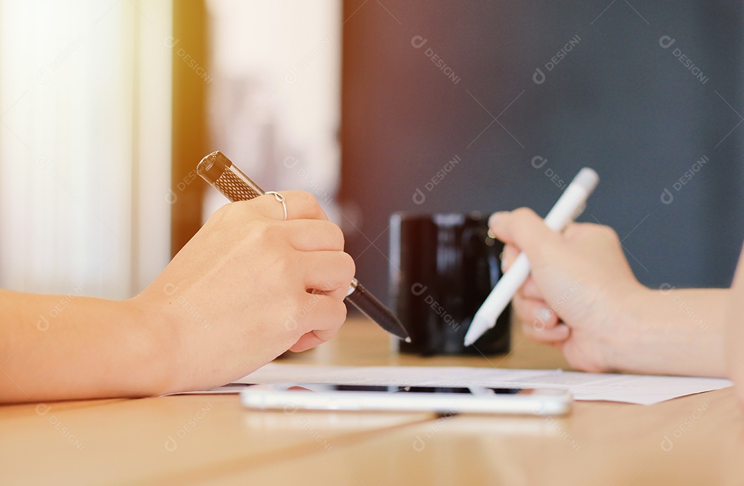 Fechar as mãos de duas empresárias assinando um documento