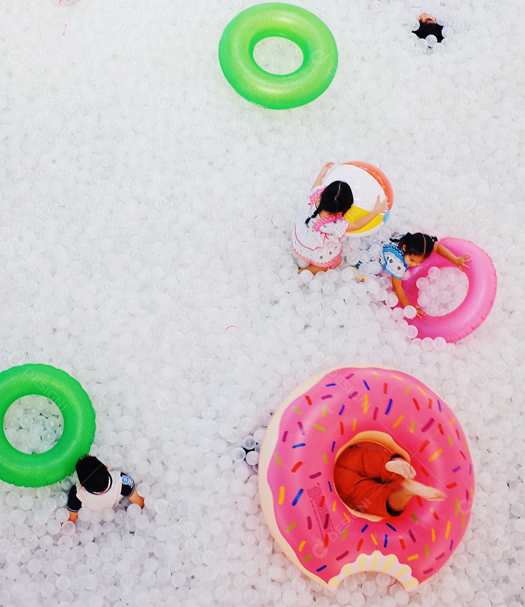 Crianças brincando com boia na piscina de bolinhas