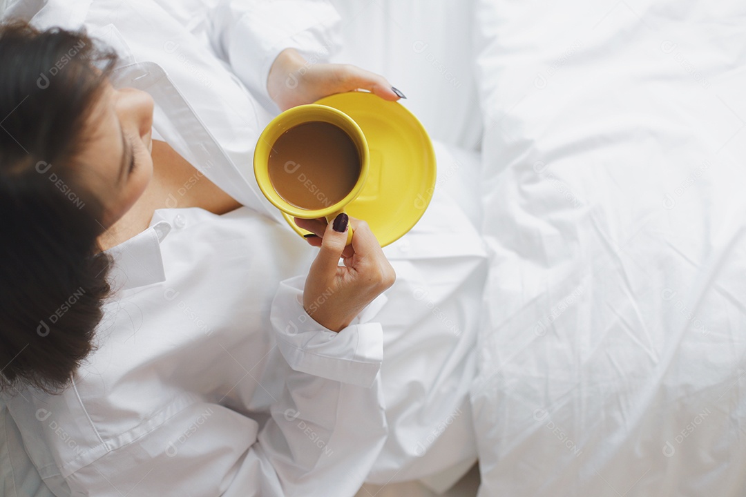 Mulher segurando xícara de café quente no quarto