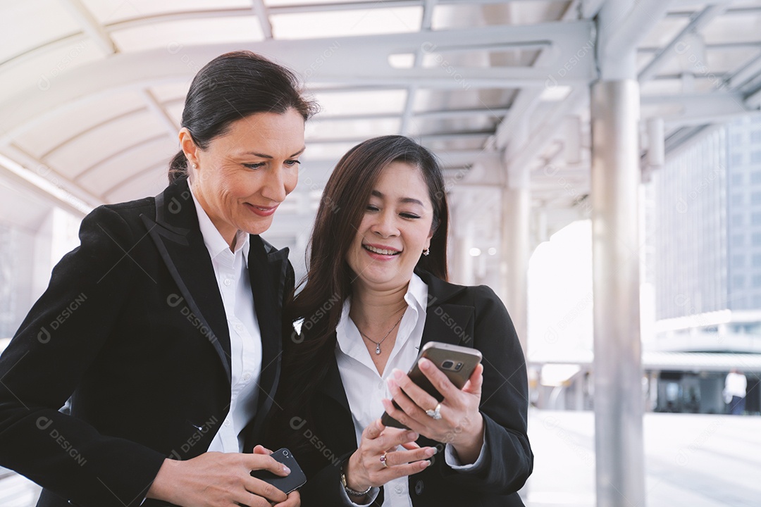 Duas mulheres de negócios seniores se encontrando e usando smartphone no moderno