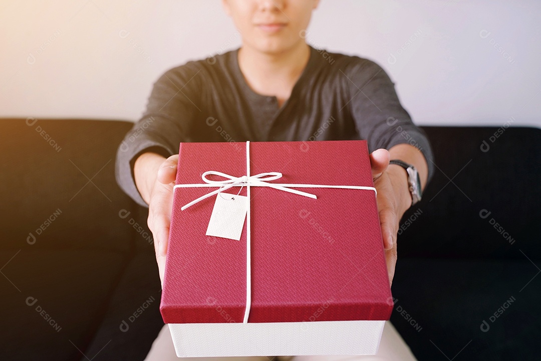 Jovem dando uma caixa vermelha de presente para presente no conceito de férias
