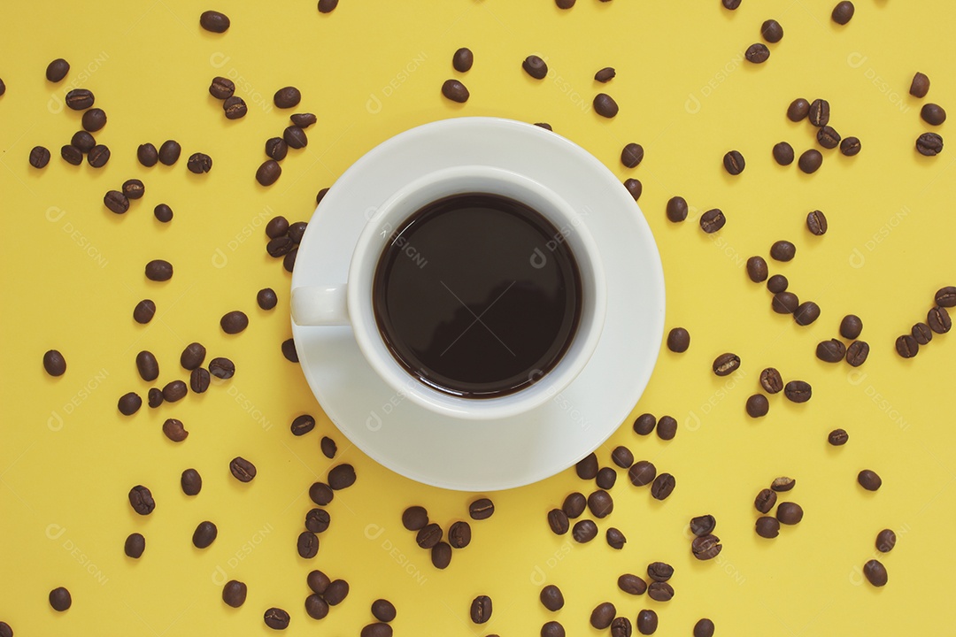 Xícara branca com café grãos de café torrados espalhados sobre a mesa