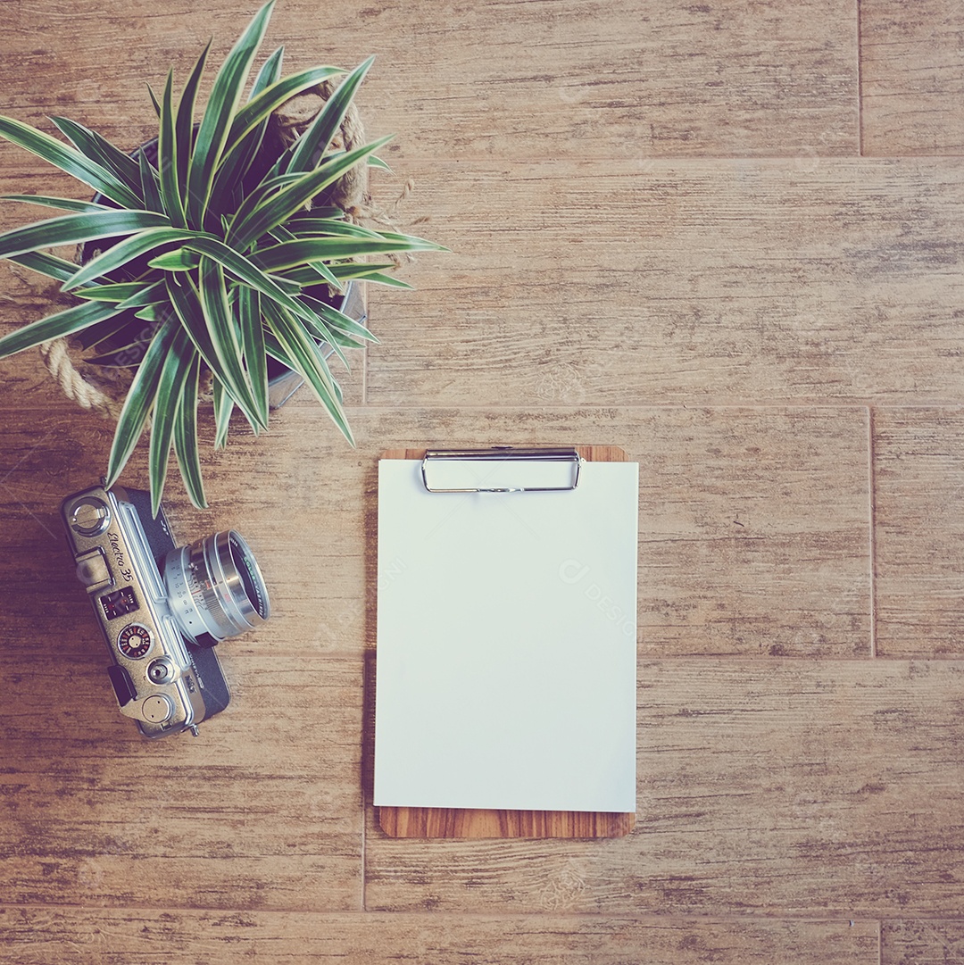 Câmera fotográfica com prancheta sobre mesa de madeira