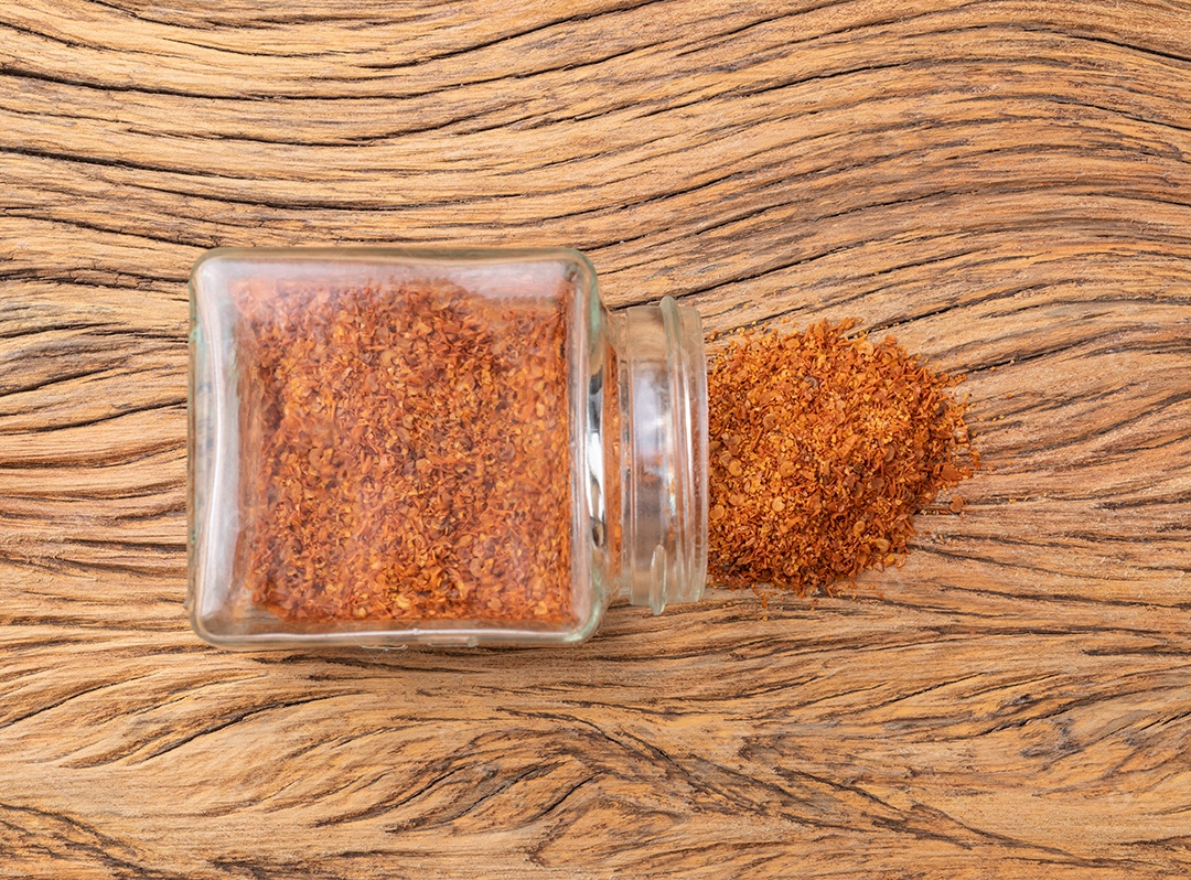 Closeup de pimenta caiena em um pote de vidro sobre a mesa de madeira.