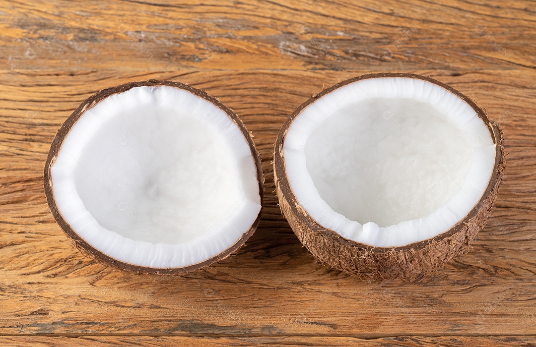 Coco rachado meia fruta sobre a mesa de madeira.