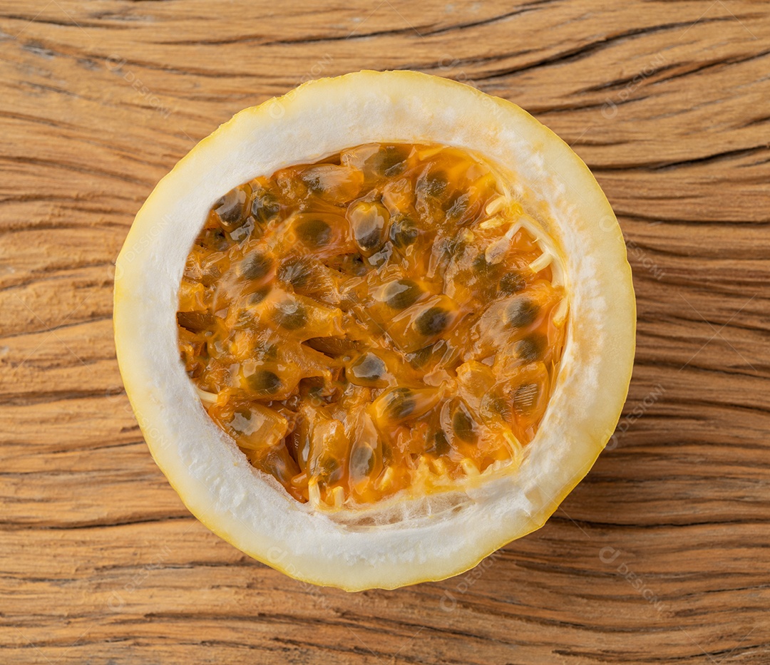 Close de um maracujá cortado sobre a mesa de madeira.