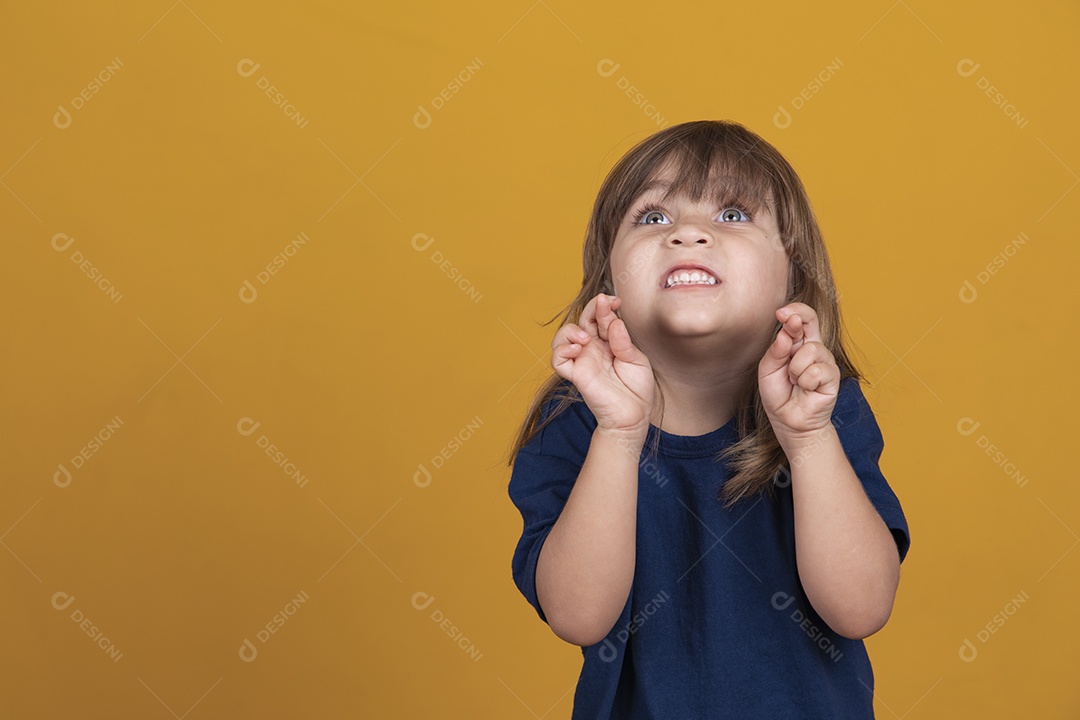 linda criança garota caucasiana com os dedos cruzados desejando sorte