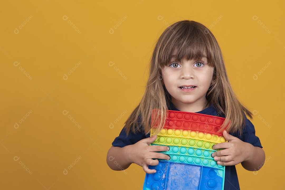 Menina alegre joga em um brinquedo pop de plástico multicolorido Jogando em casa durante as férias de verão