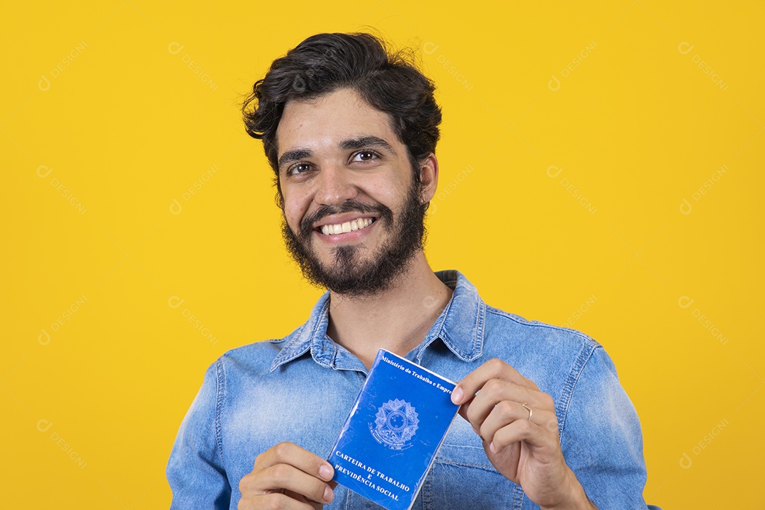 Homem jovem barbudo segurando carteira de trabalho sobre fundo amarelo