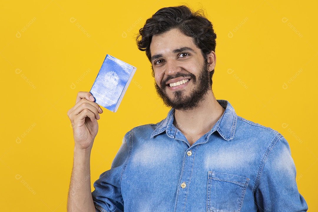 Homem jovem barbudo segurando carteira de trabalho sobre fundo amarelo